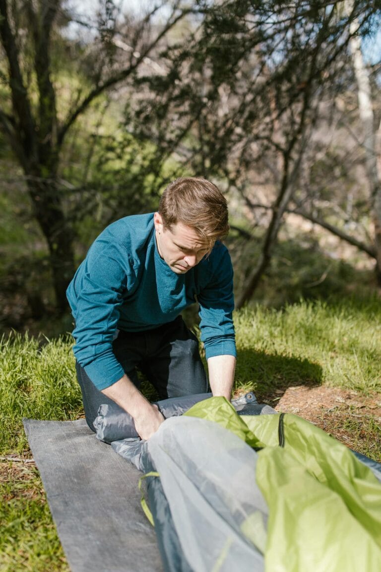 A man assembling a tent in a sunlit forest setting, perfect for camping enthusiasts.