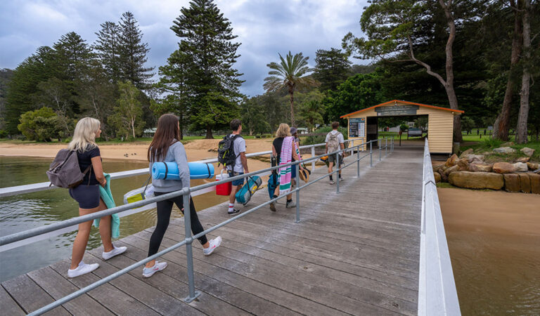 Campers walking across the ferry wharf arriving at The Basin campground 768x450